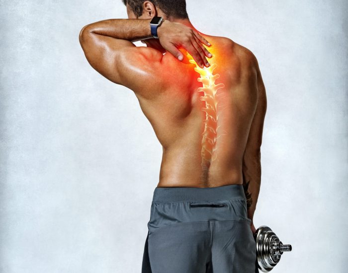 Neck pain. Muscular man suffering from backache. Photo of man with painful area highlighted in red on grey background